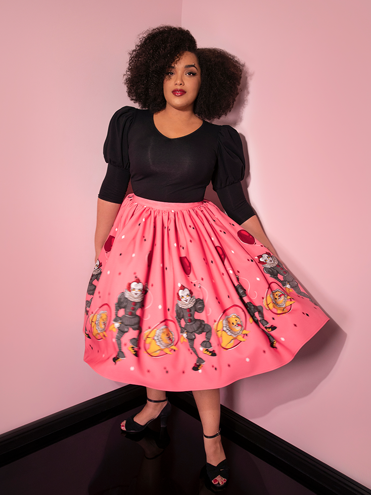 Showing off the skirt mid twirl, Ashleeta models the Pennywise dancing clown swing skirt in pink by Vixen Clothing.