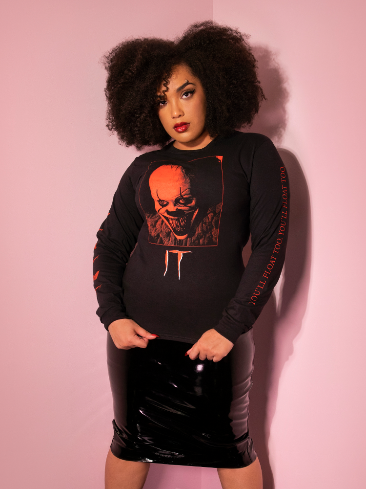 Model Ashleeta pulls on the hem of her top to show off the Pennywise Georgie boat tee by Vixen Clothing.