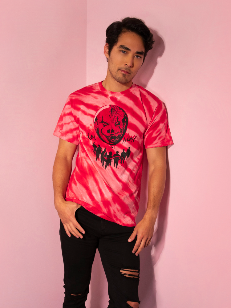 Leaning against a pink wall, Ethan models the Come Home red tie dye tee by Vixen Clothing.