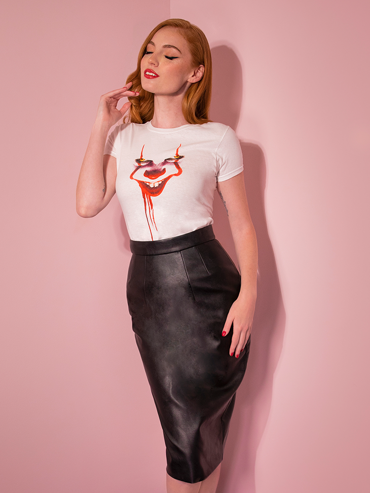 With her eyes closed and her hands in her hair, Emily models the Pennywise poster art tee by Vixen Clothing.