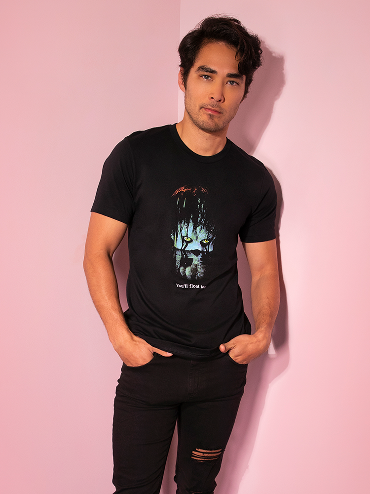 Looking at the camera with his hands in his front pockets, Ethan shows off the Pennywise flat tee by Vixen Clothing.