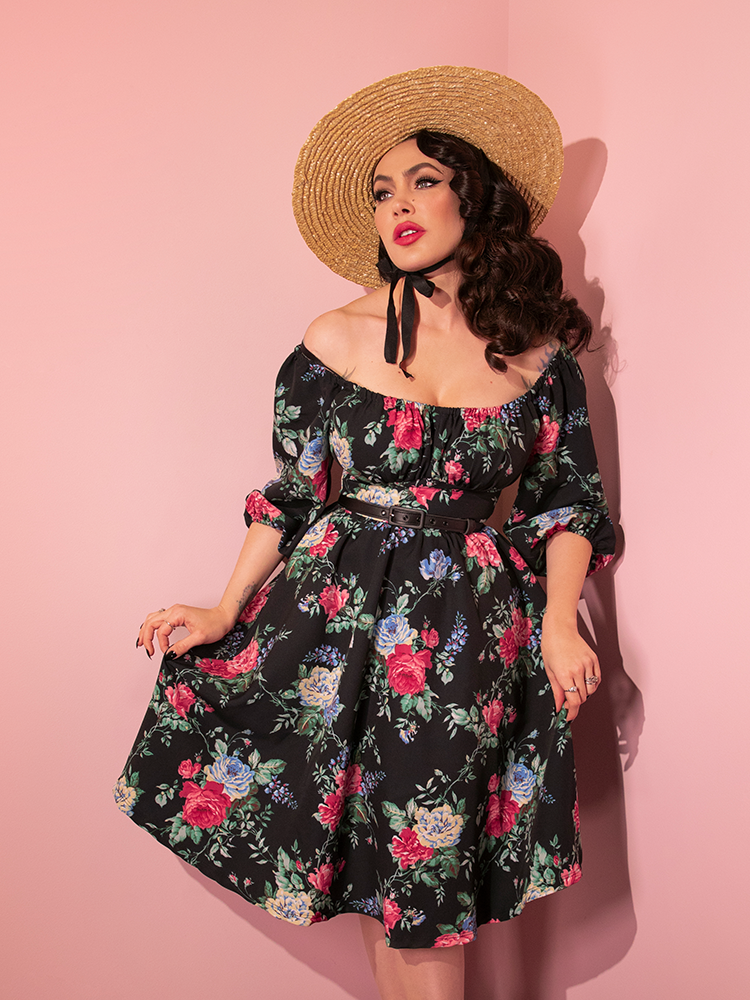 Micheline Pitt posing in the Vacation Dress in Black Rose Print to show off the skirt section.