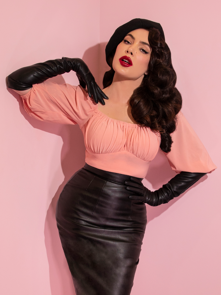 A closeup of Micheline Pitt modeling the Vacation top in pink paired with black gloves and a black skirt.