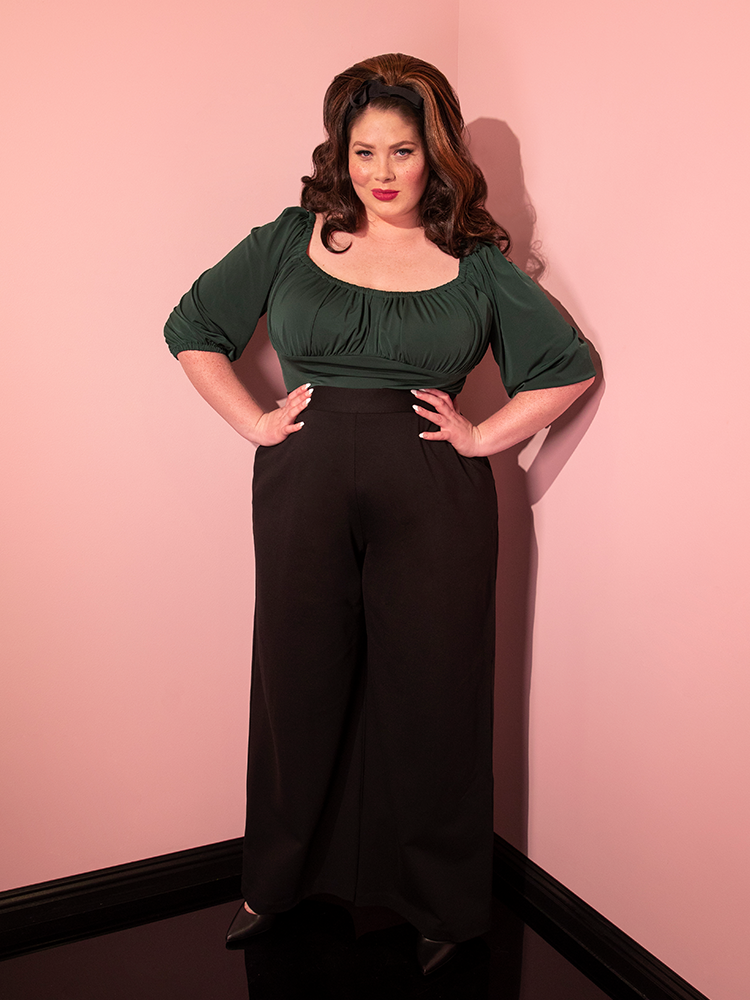 The Vacation Pants in Black Ponte being worn by brunette model with forest green retro top and black shoes.
