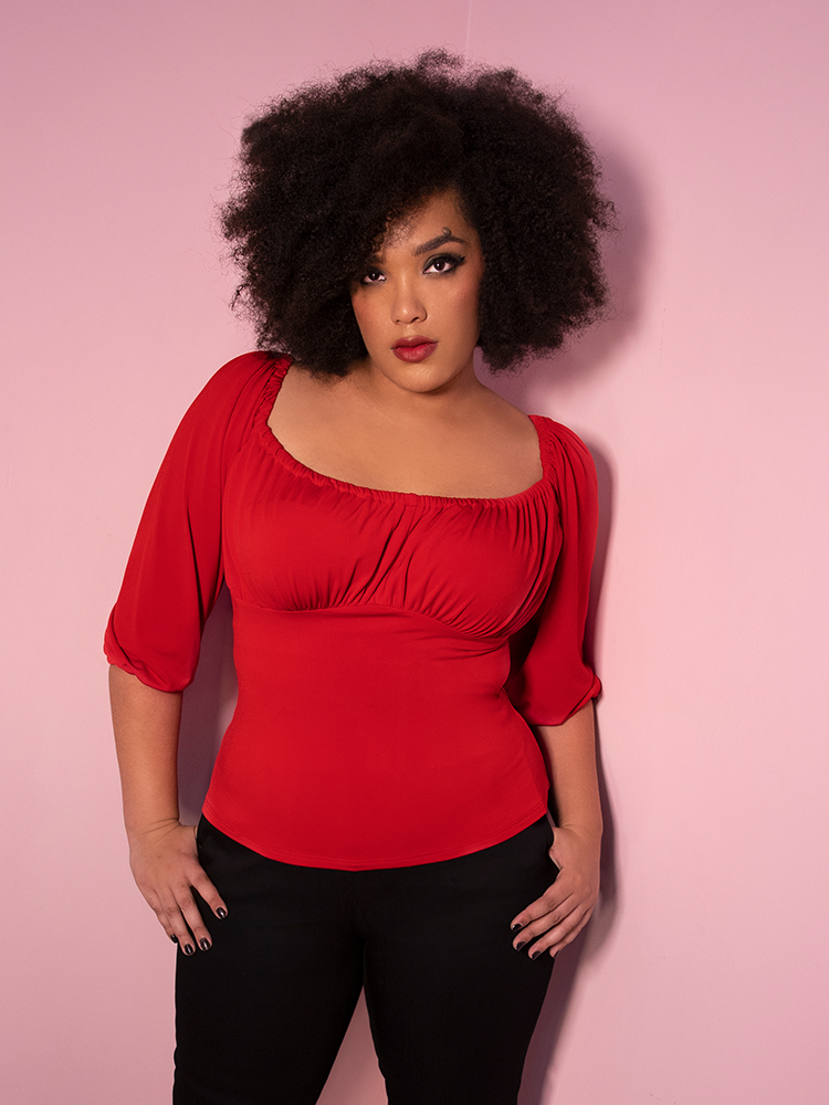 3/4 shot of model Ashleeta wearing the retro top Vacation Blouse in Red along with black fitted pants.