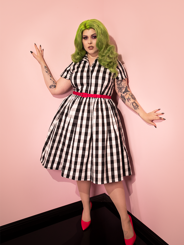 Green haired female model posing in the BEETLEJUICE inspired BEETLEJUICE™ Adam Maitland Shirt Dress from retro inspired dress brand Vixen Clothing.