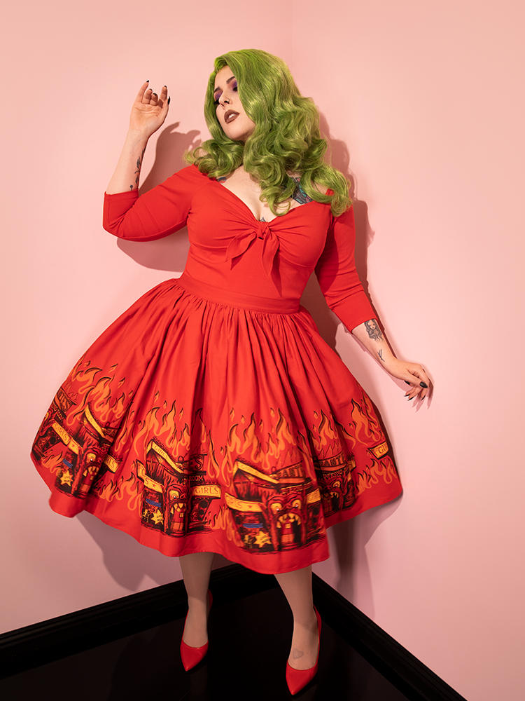 The BEETLEJUICE™ Dante's Inferno Swing Skirt modeled by green haired model also modeling a retro low-cut red top.