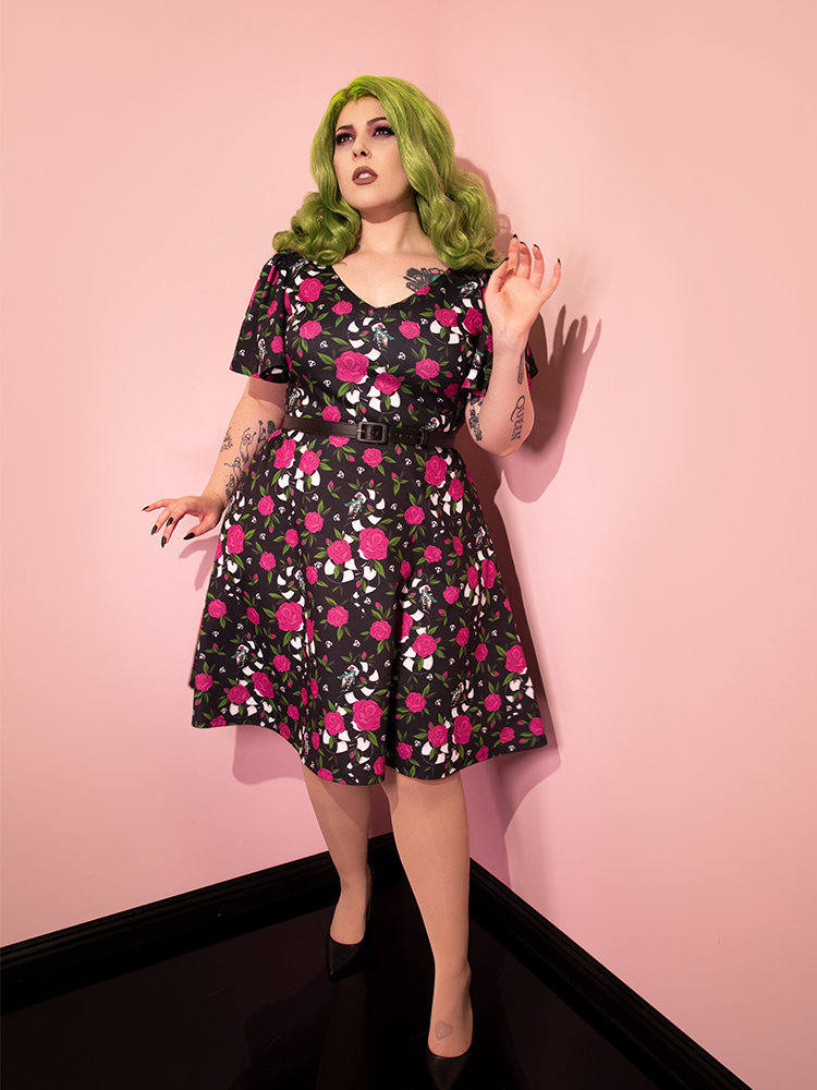Full length shot of female model wearing the BEETLEJUICE™ Sandworm & Roses Swing Dress with matching black shoes.