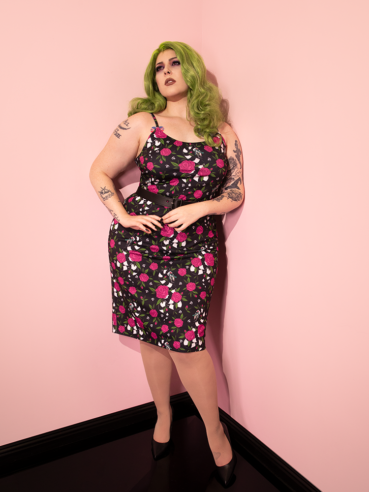 Green haired model looks wistfully up into the ceiling while posing in the BEETLEJUICE™ Sandworm & Roses Peplum Wiggle Dress.