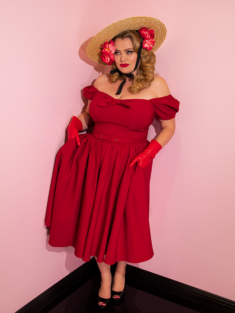 Blondie with her hands in her pockets of the Vixen Swing Dress in Red.