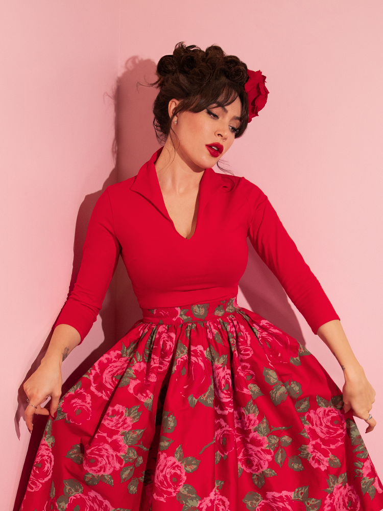 Micheline Pitt pulling out the sides of her pink rose design adorned skirt to go along with her Vixen Top in Ravishing Red. 