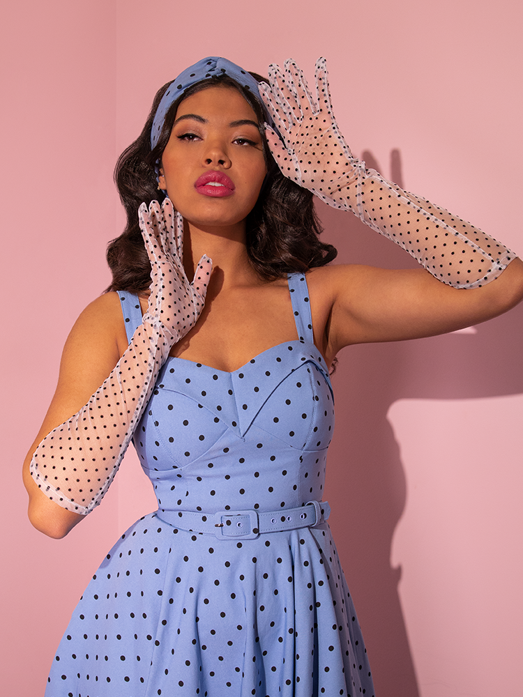 A model poses with her hands held up towards her face to show off the Mesh Polka Dot Mid Length Gloves in White.