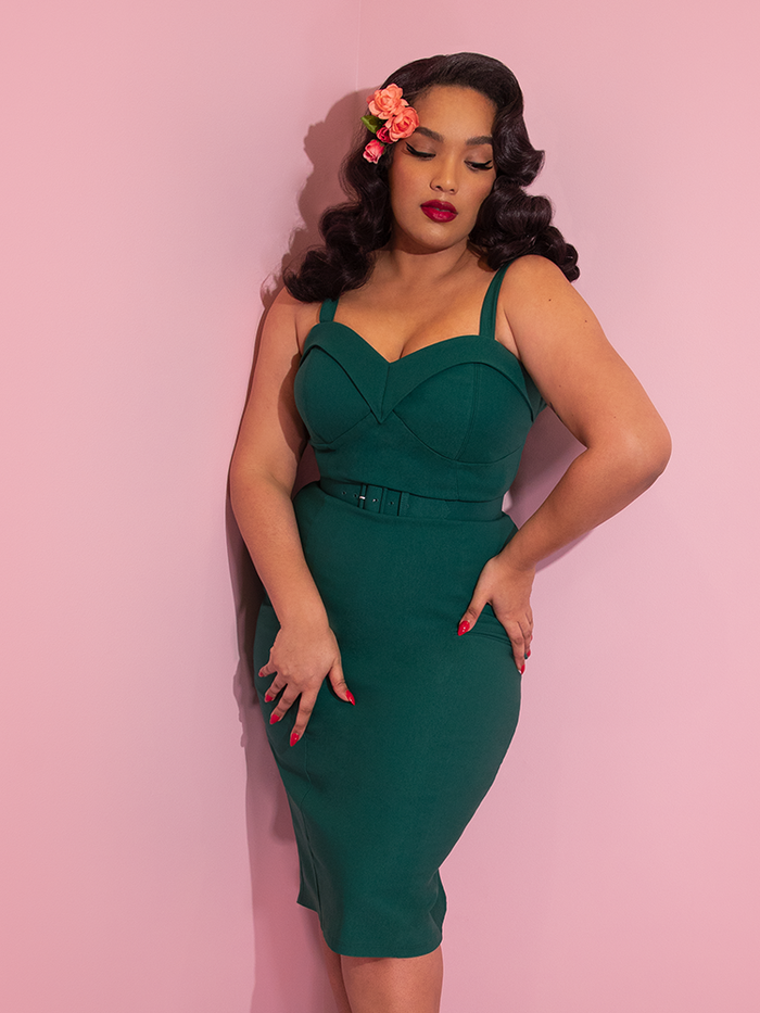 A closeup of Ashleeta with flowers in her hair modeling the Maneater wiggle dress in spruce green by Vixen Clothing.
