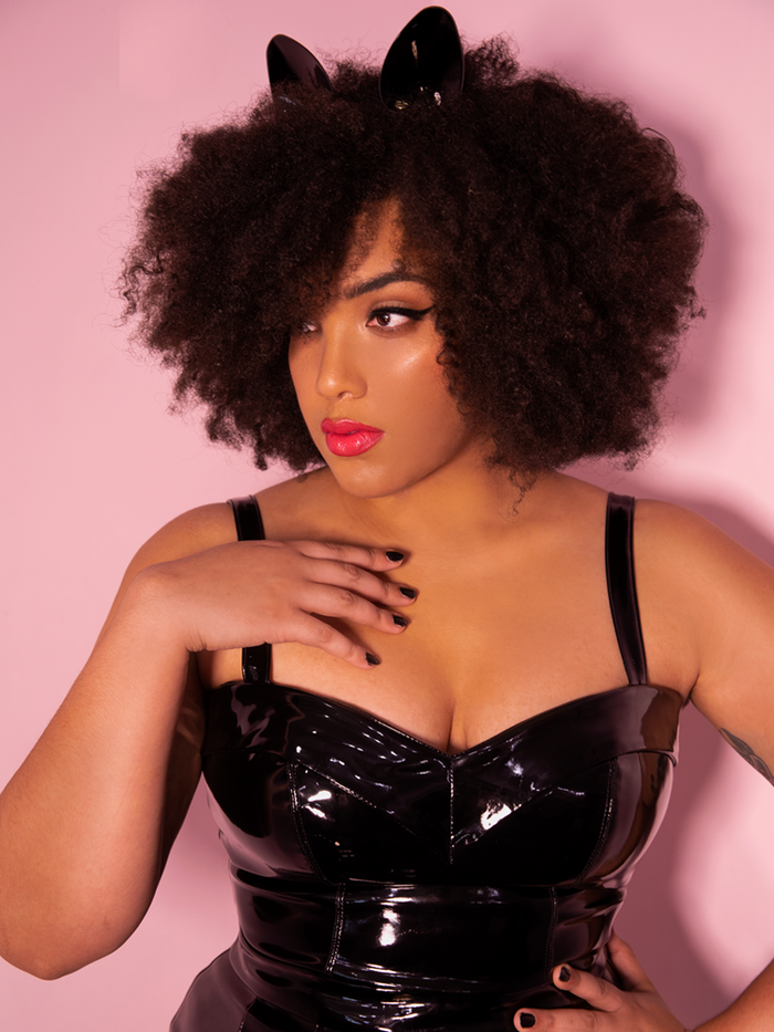A closeup of Ashleeta looking off camera modeling the Miss Kitty Maneater top in black vinyl paired with matching kitty ears.