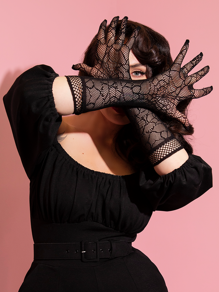 Obscuring her face, Micheline Pitt shows off the Spiderweb gloves from vintage clothing company, Vixen Clothing.