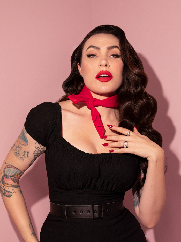 Micheline Pitt stares directly into the camera while wearing a classic retro outfit with the Vintage Bandana in Red from Vixen Clothing.