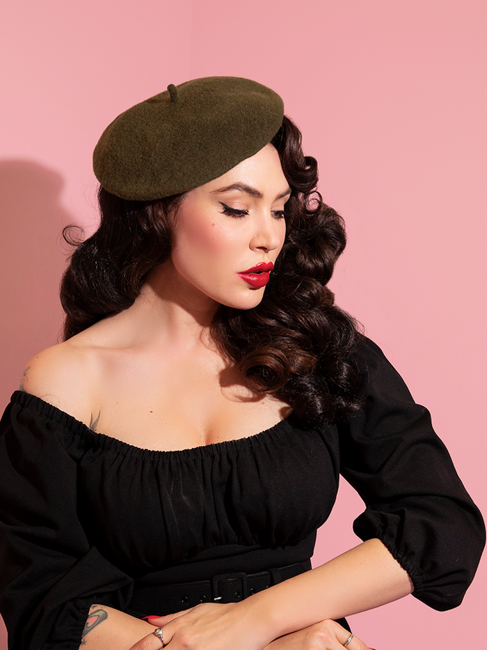 Micheline Pitt modeling the Vintage Style Beret in Olive Green with a black low-cut peasant top.