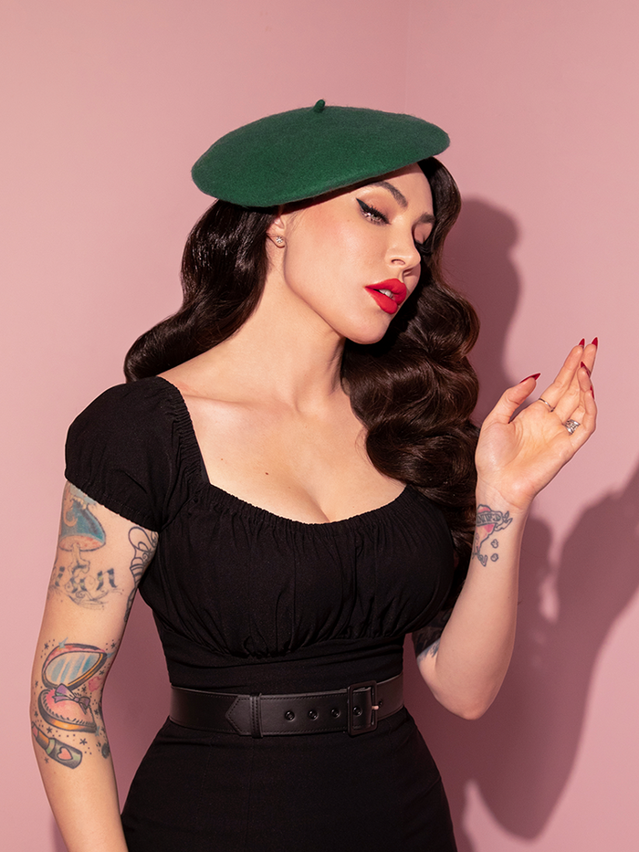 Waist level shot of Micheline Pitt modeling the Vintage Style Beret in Forest Green with an all black outfit. 