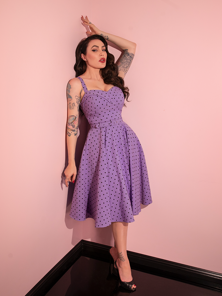 The Maneater Swing Dress in Sunset Purple Polka Dot takes center stage as Micheline Pitt playfully models for the renowned retro dress brand, Vixen Clothing.