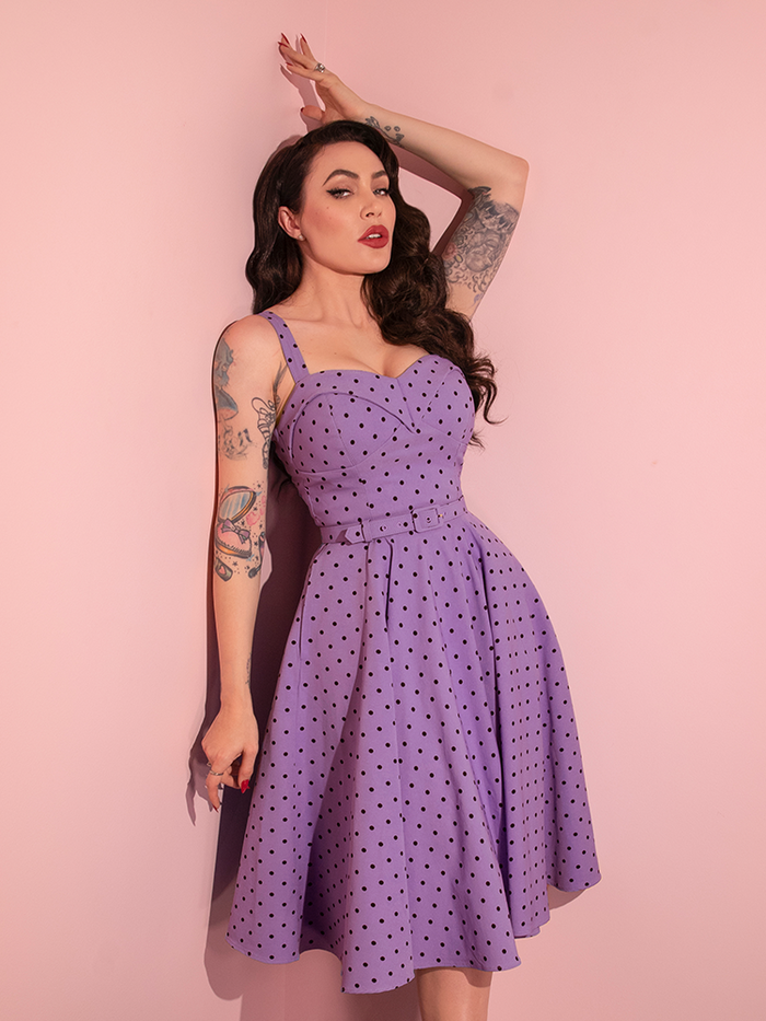 Micheline Pitt brings a playful spirit to her poses in the Sunset Purple Polka Dot Maneater Swing Dress from the retro dress brand Vixen Clothing.