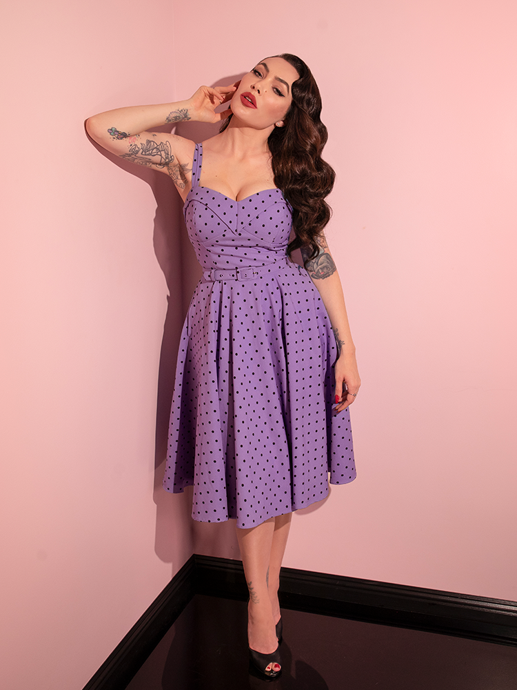 Capturing the essence of retro glamour, Micheline Pitt dons the Sunset Purple Polka Dot Maneater Swing Dress from Vixen Clothing in a series of playful poses.