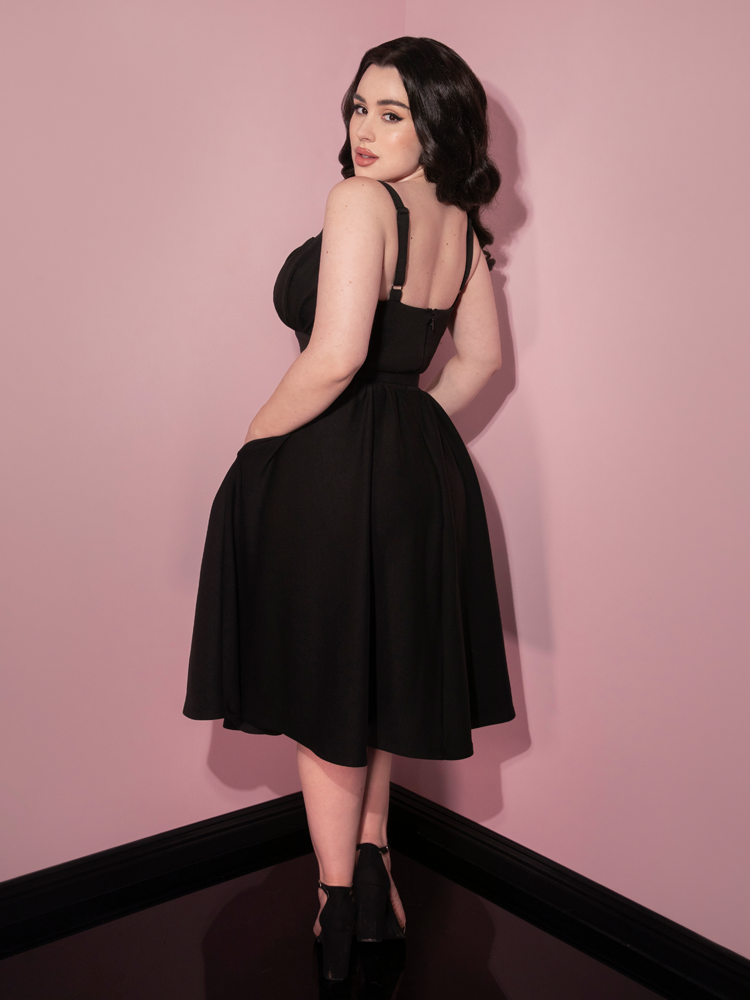 Rachel Sedory turned away in the Cozy Ingenue Dress in Black to show off the back of this new retro inspired dress from Vixen Clothing.