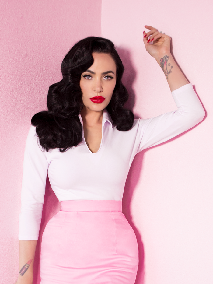 Standing in a pink room, Micheline Pitt models the Vixen Top in White.